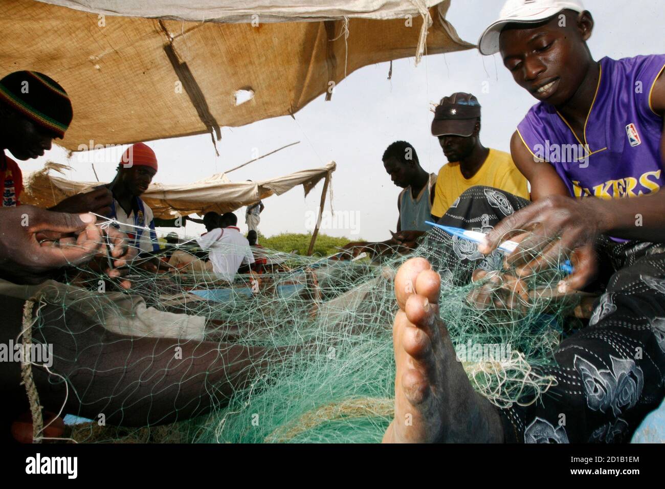 Fishermen repair their nets at a fishing port of Bissau March 10, 2009. Life in Bissau began to return to normal with some shops reopening, but people remained on edge after the killing of Guinea-Bissau's President Joao Bernado 'Nino' Vieira on March 2 in an apparent revenge attack hours after the West African country's army chief General Batista Tagme Na Wai was killed, residents and security sources said. REUTERS/Luc Gnago (GUINEA-BISSAU CONFLICT MILITARY POLITICS) Stock Photo