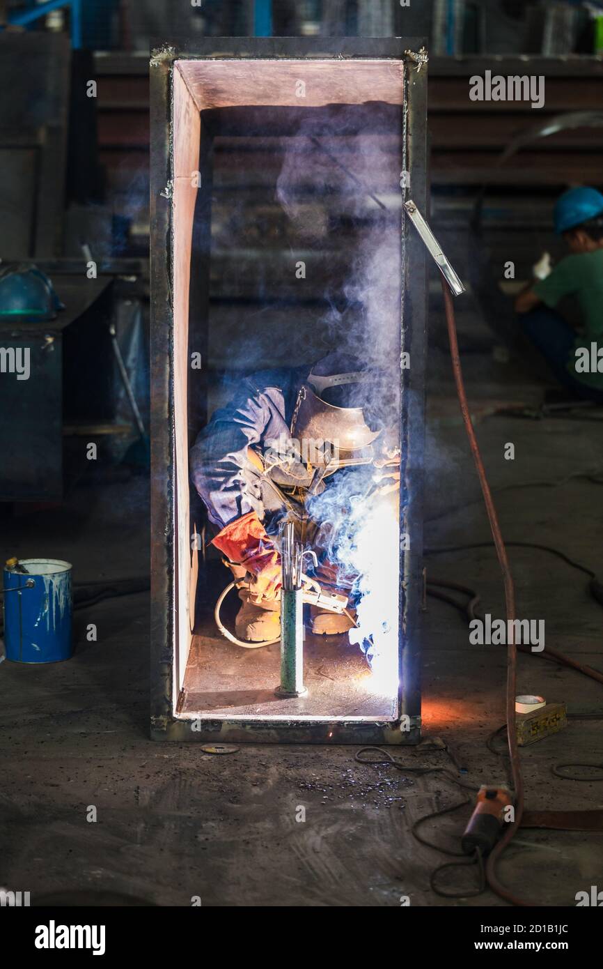 Blue-collar worker welding in the interior of a factory Stock Photo