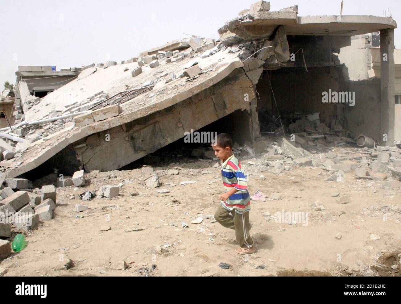 A boy runs past a damaged house after a bomb attack in Mosul, 390 km (242 miles) north of Baghdad July 9, 2009. Two car bombs exploded within minutes of each other on Wednesday in the northern Iraqi city of Mosul, killing 14 people and wounding 33, police said. REUTERS/Khalid al-Mousuly (IRAQ CONFLICT) Stock Photo