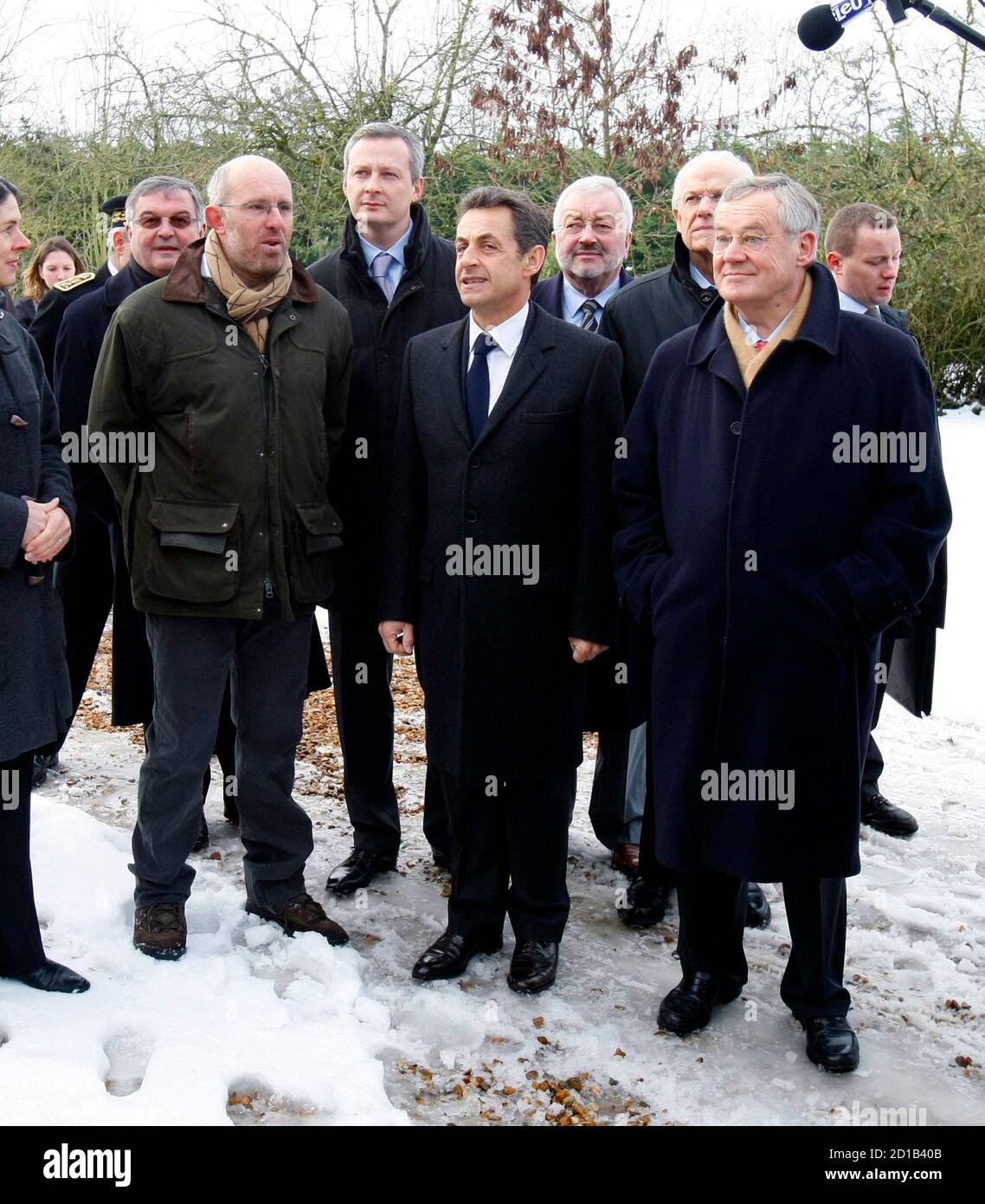 France's President Nicolas Sarkozy (C) stands in the courtyard of a farm  during a visit with Mortagne-au -Perche mayor Jean Claude Lenoir (R) and  farmer Denis Pasquert (L) in Mortagne-au-Perche, western France,