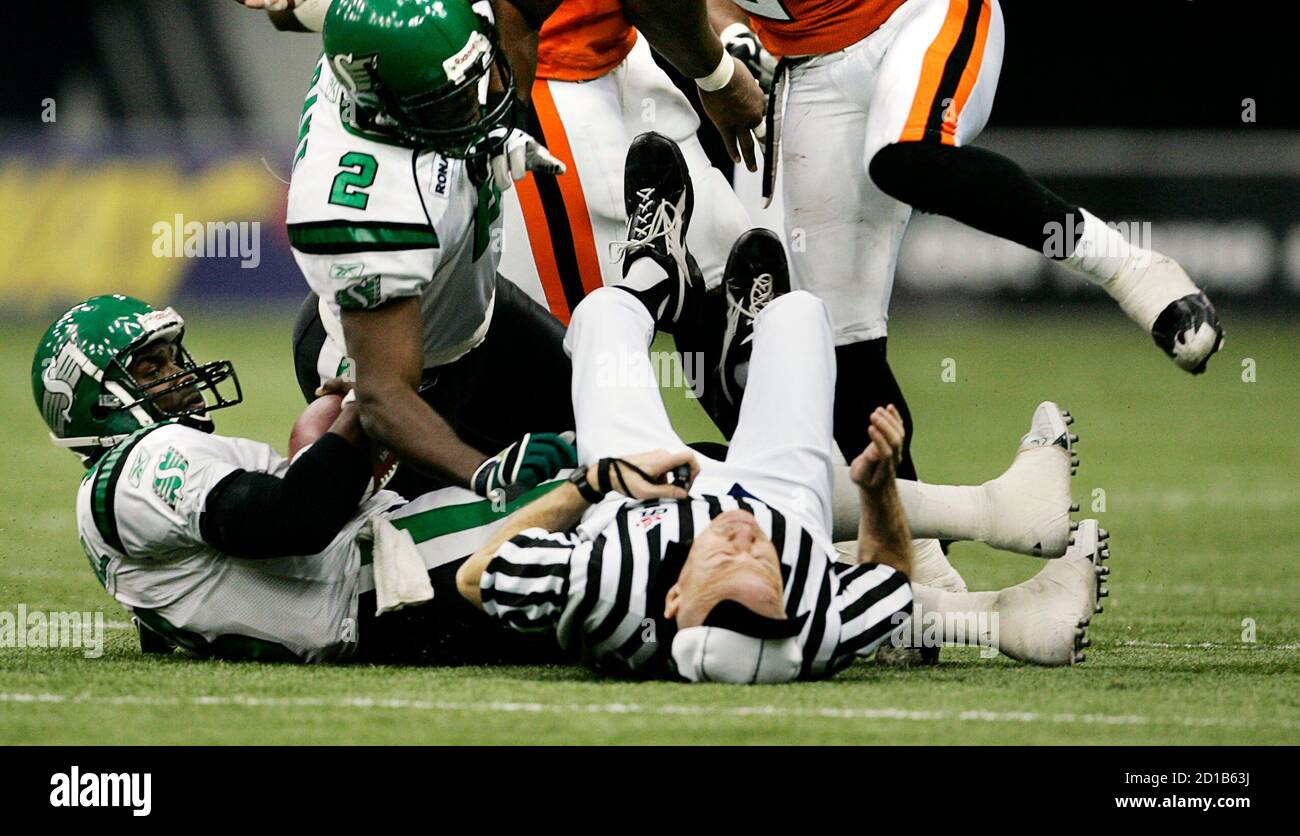 Game umpire Ian Bain (C) is knocked flat on his back by Sakatchewan  Roughriders quarterback Marcus Crandell (L) during fourth quarter Canadian  Football League play in Vancouver, British Columbia October 1, 2005.