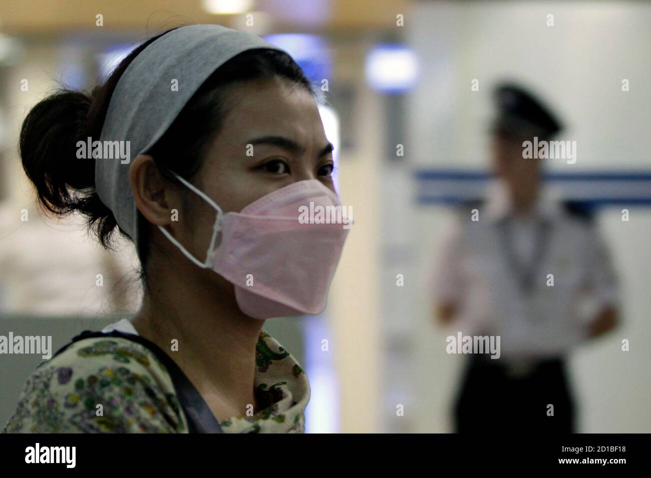 A passenger wearing protective mask arrives at Shanghai Pudong Airport June 12, 2009. The World Health Organization declared an influenza pandemic on Thursday and advised governments to prepare for a long-term battle against an unstoppable new flu virus. REUTERS/Aly Song (CHINA SOCIETY HEALTH) Stock Photo