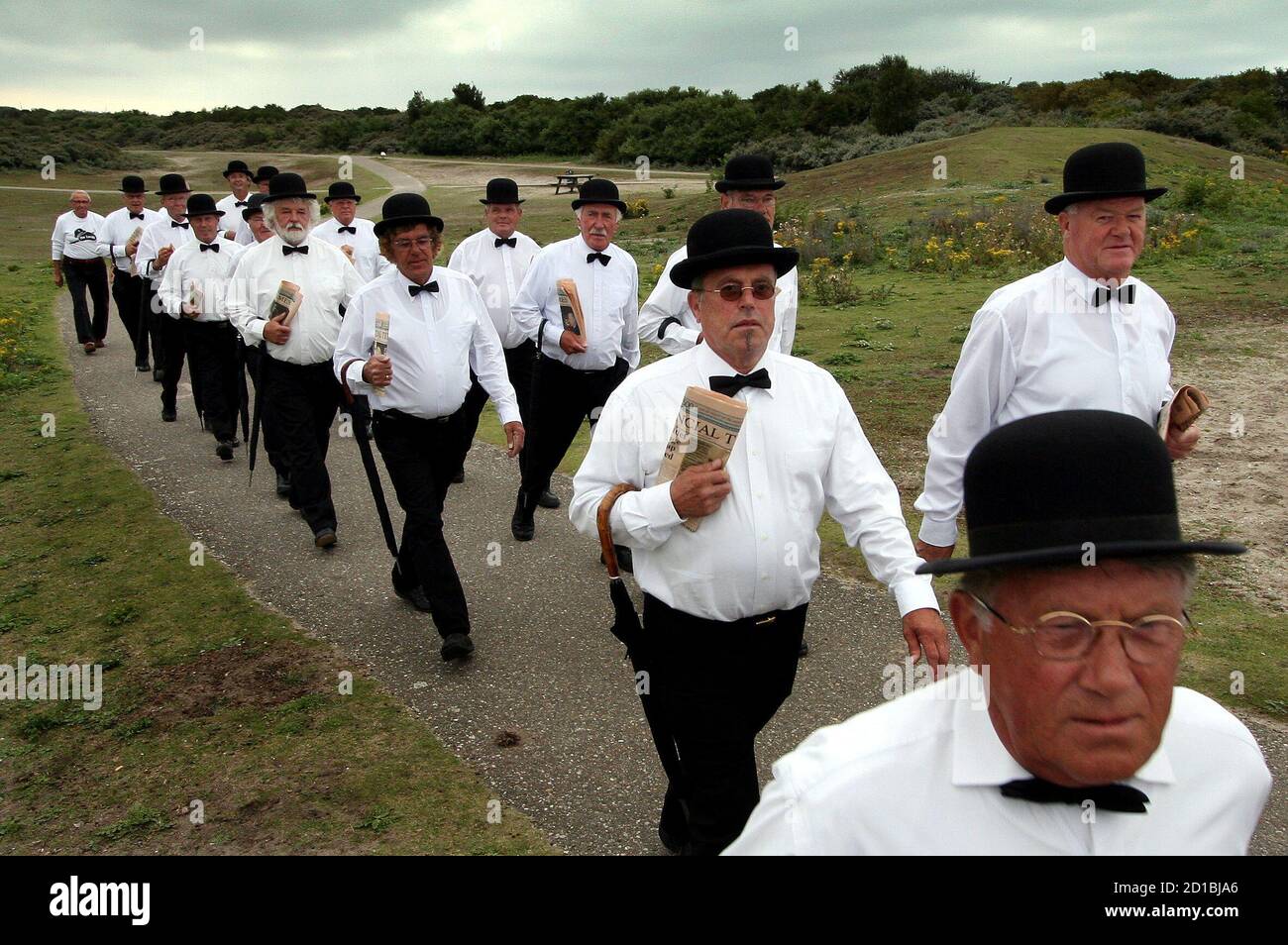 Members of a men's walking club known as 'The Lords', walk through the dunes of the beach resort of Hoek van Holland in western Holland August 11, 2005. Dressed in traditional British outfits, 'The Lords' participated in an annual walking competition, 'The Avond vierdaagse', over four evenings with a daily walk of 10 kilometres (6 miles). Picture taken August 11, 2005. REUTERS/Jerry Lampen  JFL/PN Stock Photo