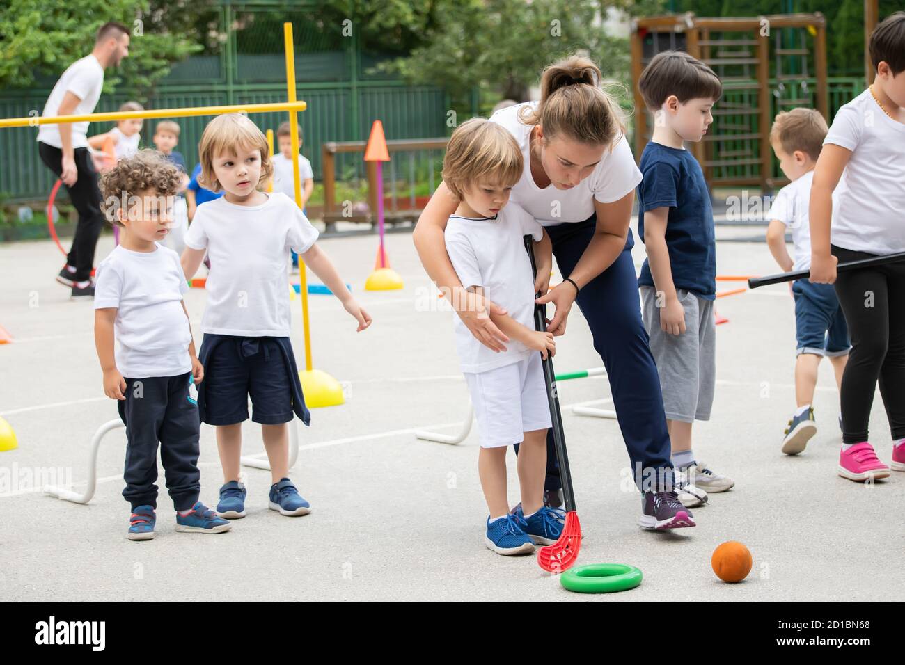 Group of children playing hockey within polygon. Sport school. Coach