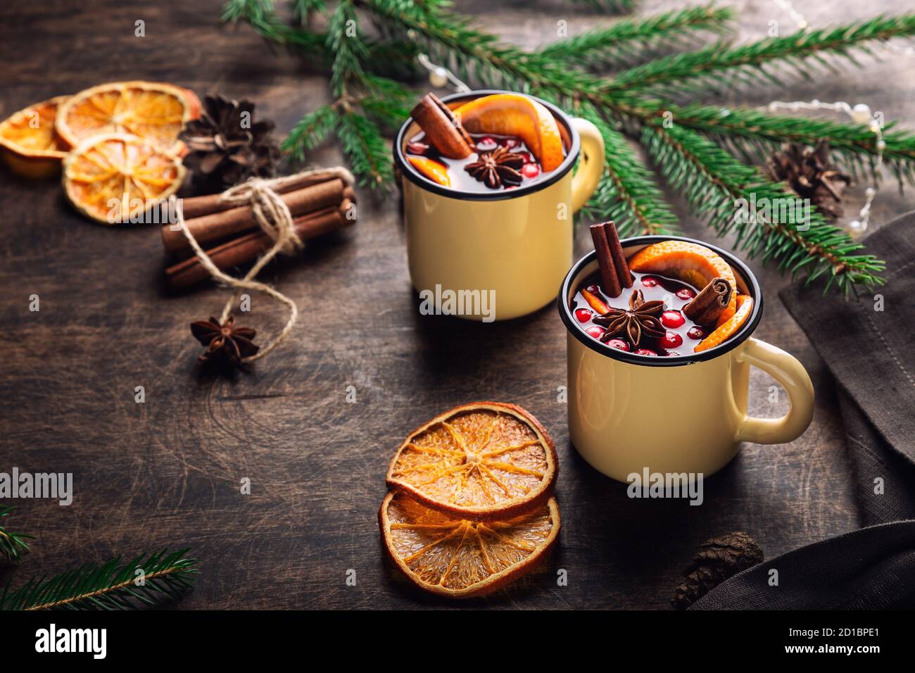 Christmas mulled wine with cranberries, orange and spices in mugs on rustic plywood background. Traditional hot winter drink. Stock Photo