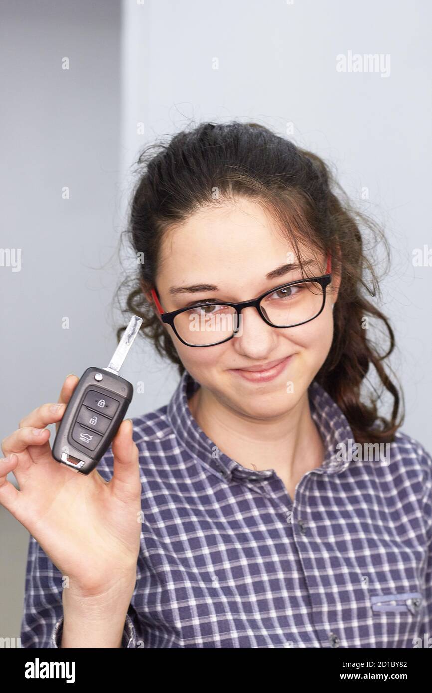 a young girl in glasses and a shirt holds the car keys in her hand