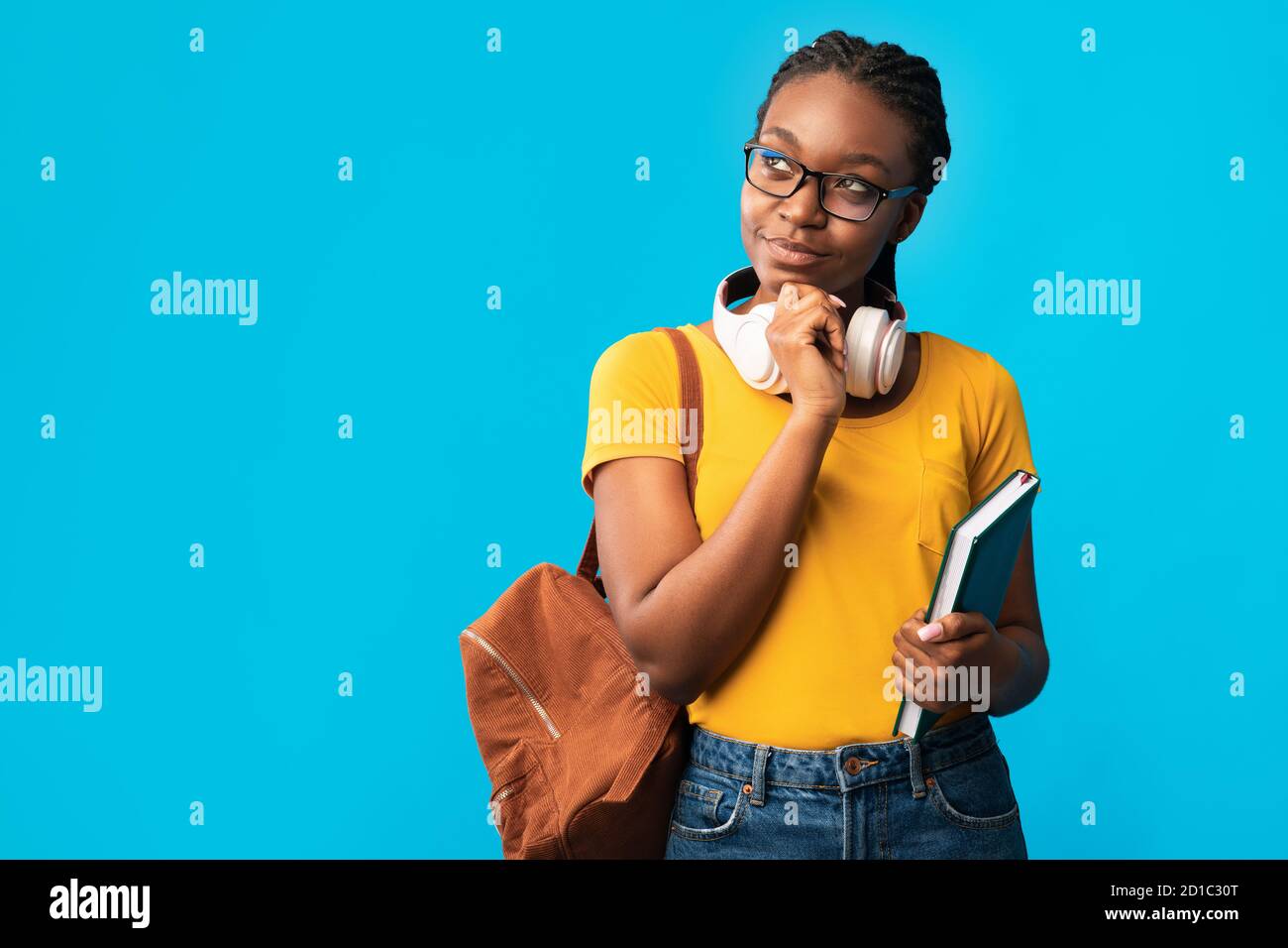 Thoughtful African Woman Student Thinking Holding Books On Blue Background Stock Photo