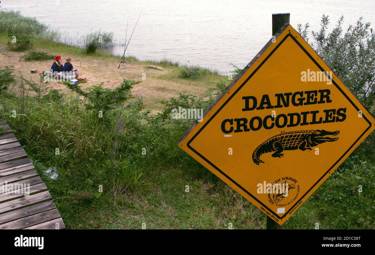 - PHOTO TAKEN 12APR06 - Fishermen cast their lines near a sign warning of the dangers of crocodiles on the banks of St Lucia estuary, about 200 km (124 miles) north of the coastal city of Durban, South Africa April 12, 2006. [Humans and big beasts have lived side by side in Africa since the dawn of our species, but rapid population growth is now stoking friction with dangerous animals, experts say.] Stock Photo