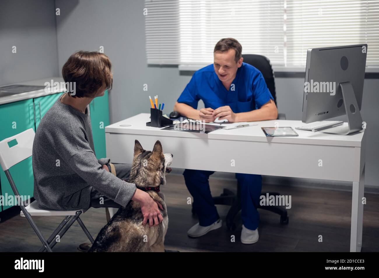 A male doctor talking to a young woman about her dogs diagnosis. Stock Photo