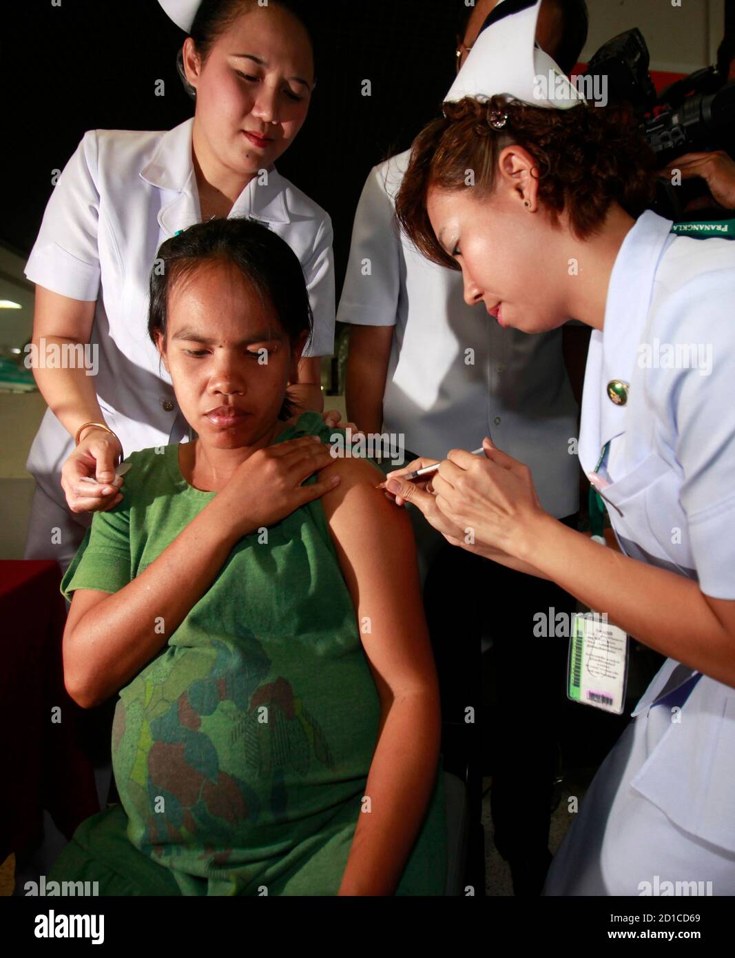 Boonya Klaer-orm, 25, who is 8 months pregnant, receives a H1N1 influenza  vaccine shot from a medical staff at a hospital in Nonthaburi province, on  the outskirts of Bangkok January 11, 2010.