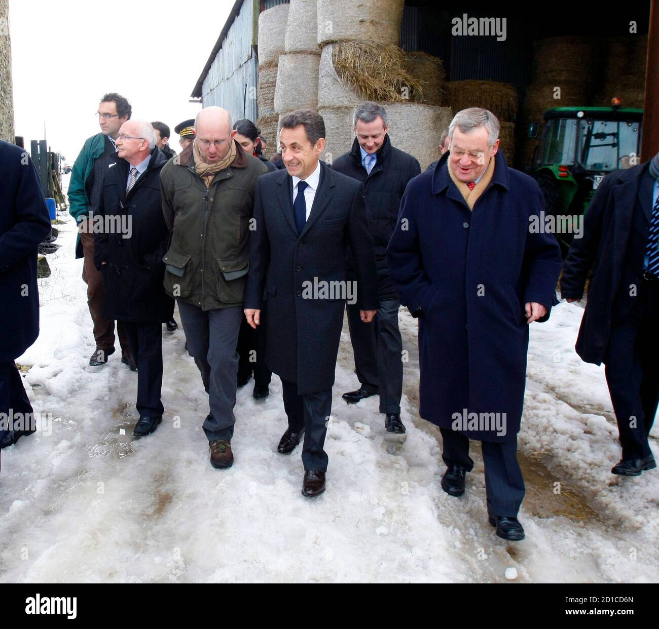 France's President Nicolas Sarkozy (C) walks in the courtyard of a farm  during a visit with Mortagne-au -Perche mayor Jean Claude Lenoir (R) and  farmer Denis Pasquert (L) in Mortagne-au-Perche, western France,