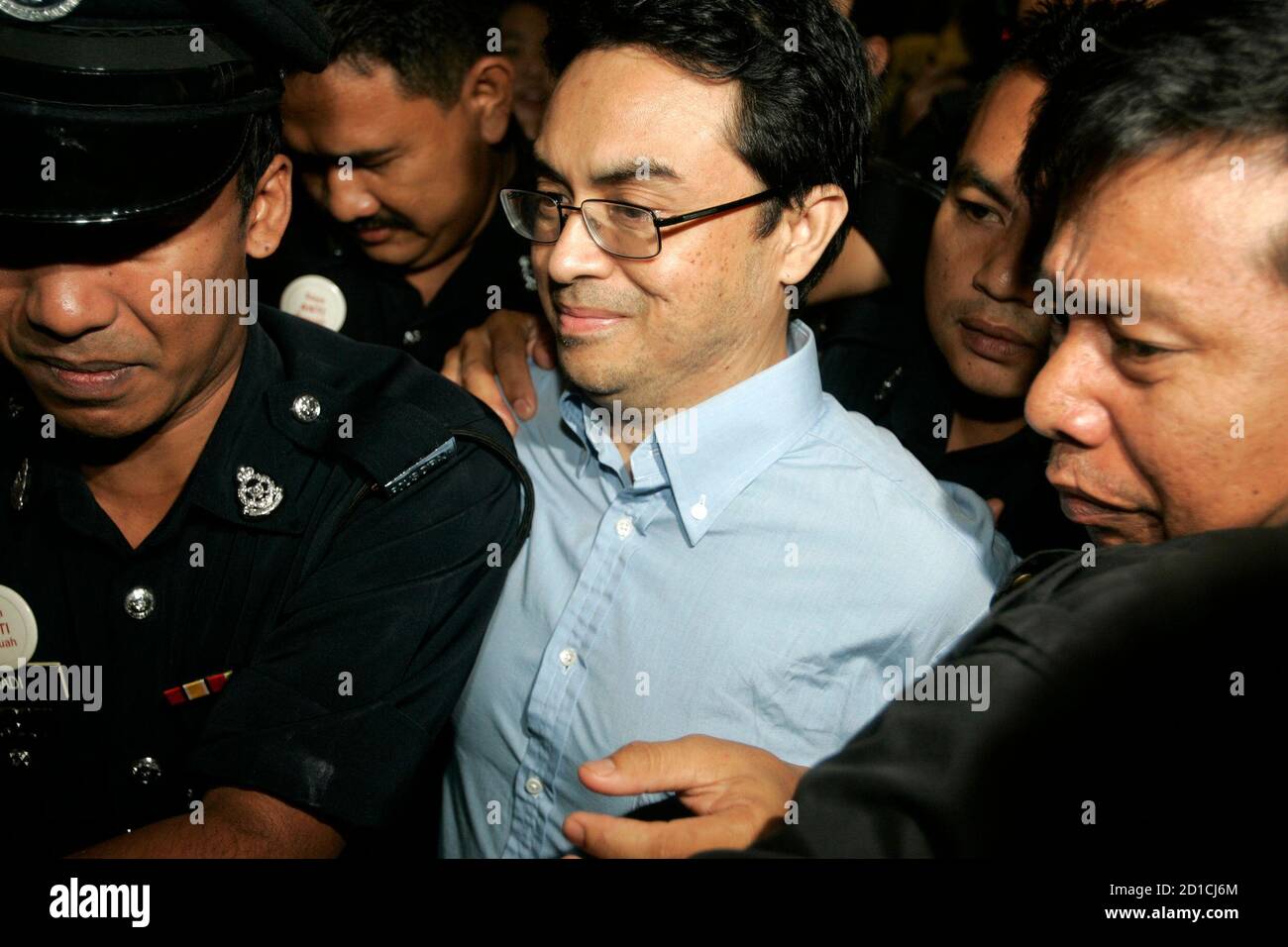 Abdul Razak Abdullah Baginda is escorted by police as he arrives at a courthouse in Shah Alam outside Kuala Lumpur June 4, 2007. Malaysia postponed on Monday the trial of a prominent political analyst accused of involvement in the murder of a Mongolian model, Altantuya Shaariibuu, feeding months of frenzied speculation about government links to the case.   REUTERS/Zainal Abd Halim (MALAYSIA) Stock Photo