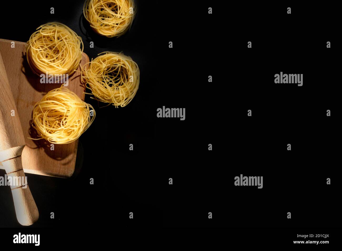 Rolled tagliatelle shape of italian pasta on black stone background