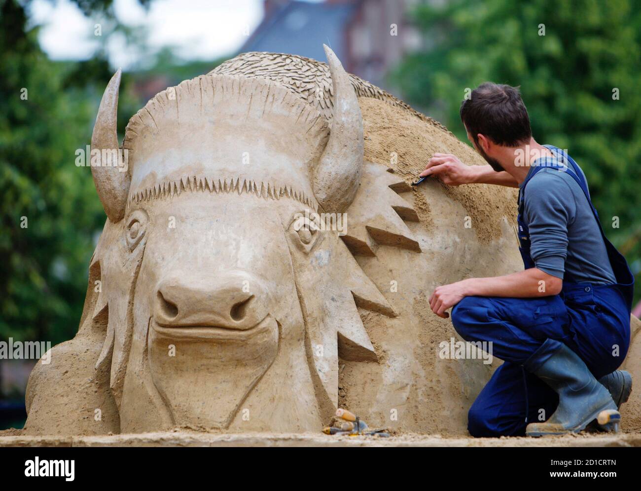 An artist works on a sand sculpture at the seventh international sand sculptures festival 'Sandsation' in Berlin June 6, 2009. Twelve sculptures of up to 4.5 metres in height, each one constructed as an imaginary urban world, will enter the competition for the world champion title in sand sculpture construction. With an 8 metres high show piece the artists will also take a joint look into the future ? ?Berlin in the year 2222? is the theme for this collectively created sculpture.The festival will open its doors to the public on June 7 till August 30 near Berlin Hauptbahnhof (central station).  Stock Photo