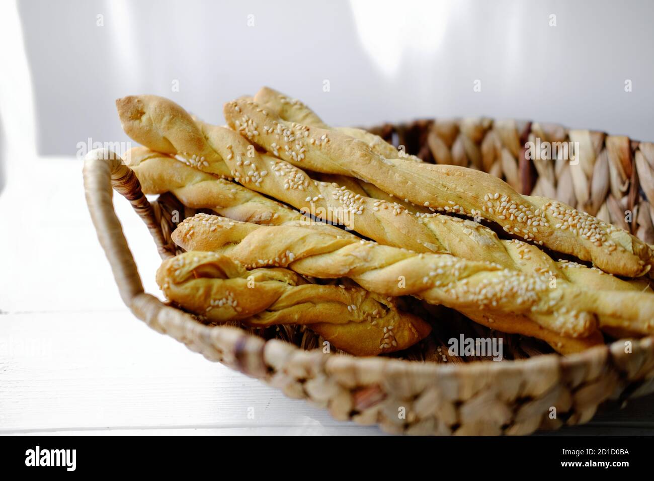 Italian grissini or salted breadsticks. sesame breadsticks in a craft paper on white wooden