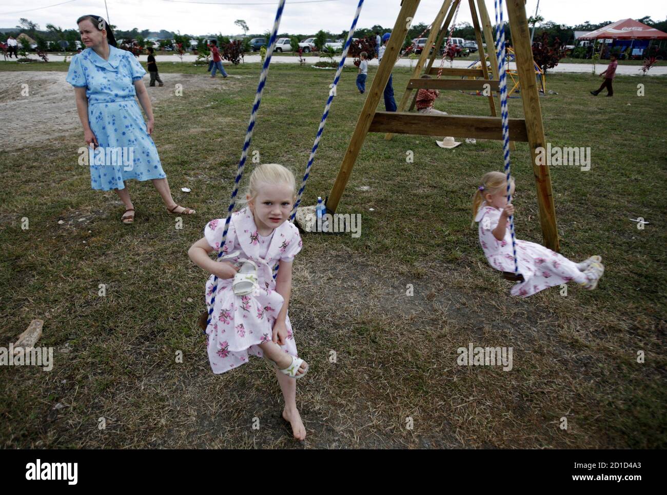 a-belizean-mennonite-woman-watches-as-her-children-play-on-a-swing-set