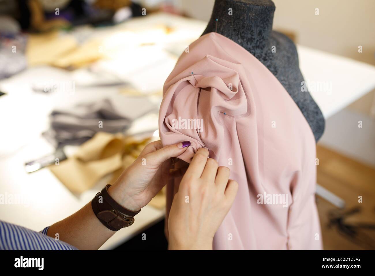 female dressmaker attach fabric to mannequin with needles. creating