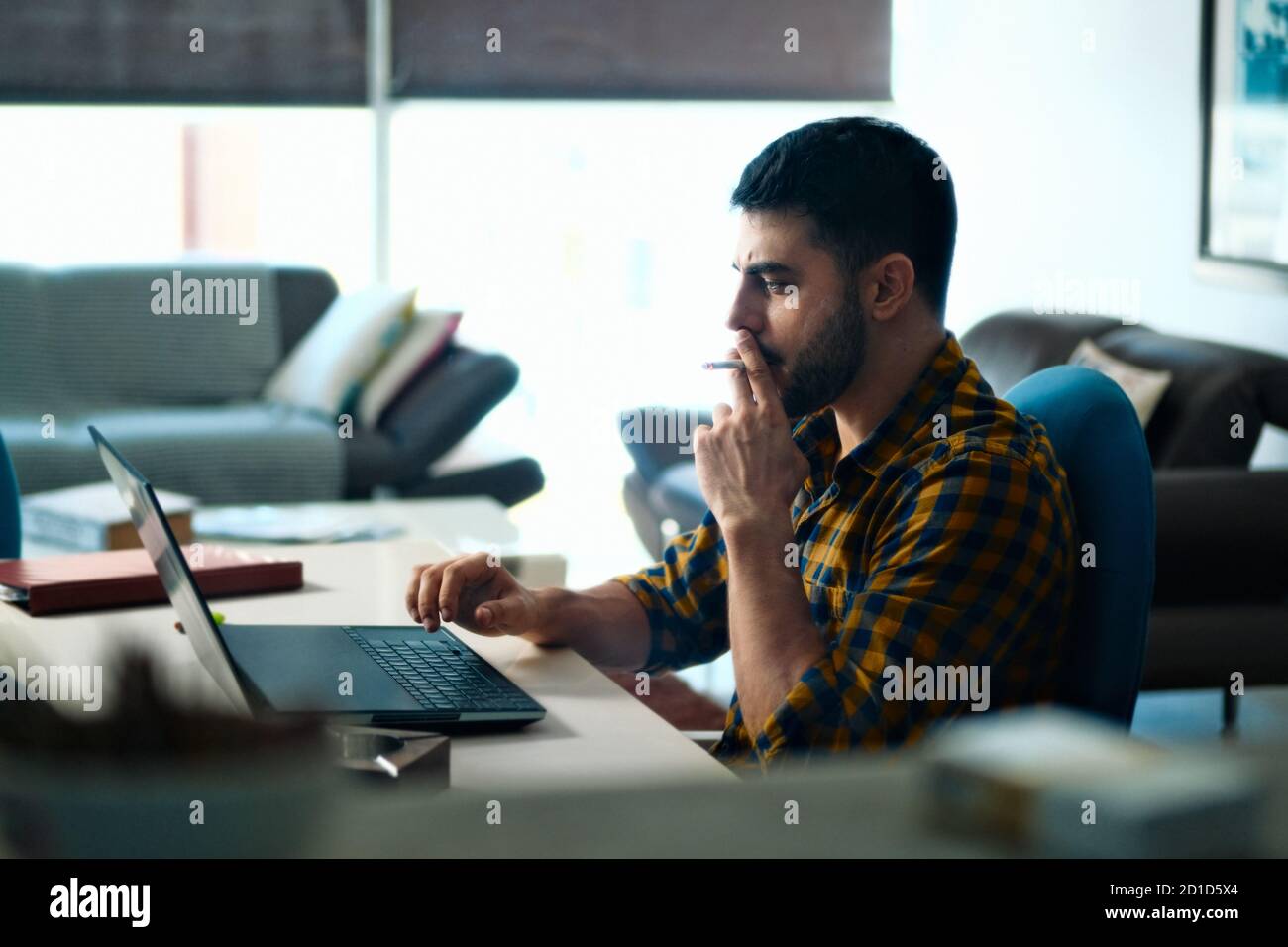 Giovane uomo di fumare narghilè mentre si lavora sul computer portatile in  cafe Foto stock - Alamy