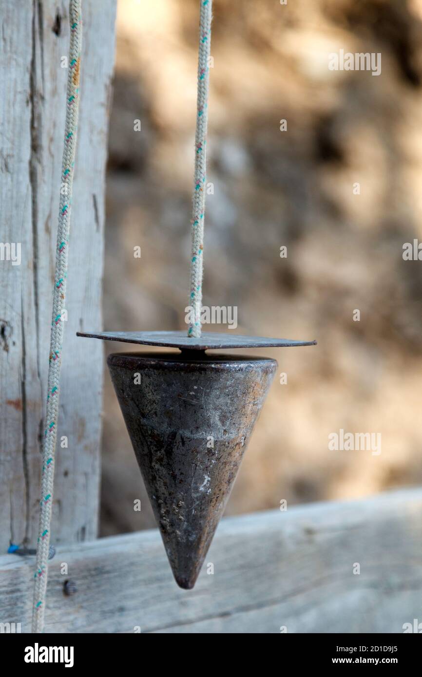 Plumb bob, or plummet, a weight, usually with a pointed tip on the bottom, suspended from a string and used as vertical reference line, or plumb-lines Stock Photo