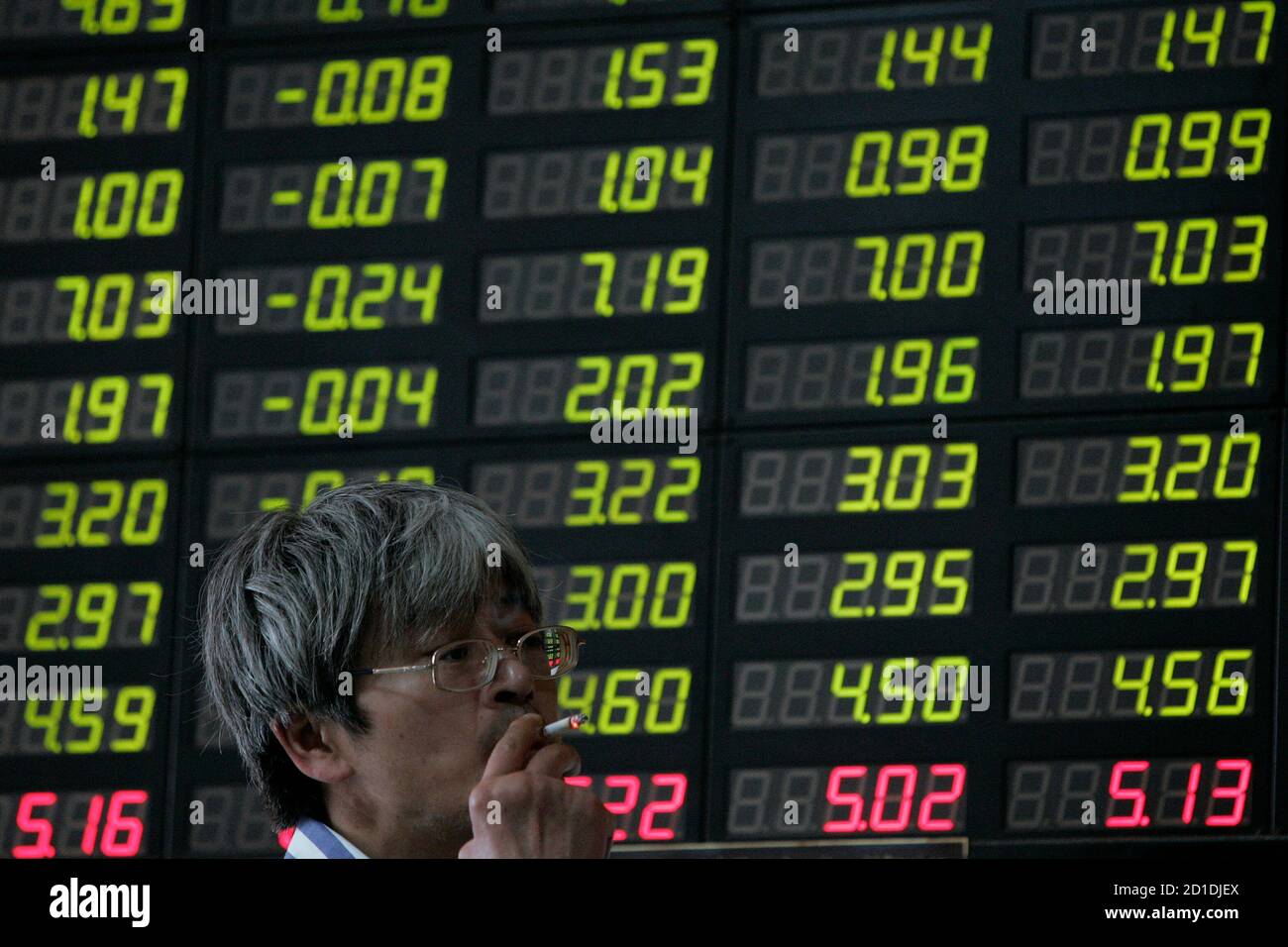 A man smokes in front of an electronic stock information board at a brokerage house in Shanghai October 6, 2008. China's stock market, resuming trade on Monday after a week-long national holiday, opened lower in response to sliding overseas markets and fears of a global economic slowdown. REUTERS/Aly Song (CHINA) Stock Photo