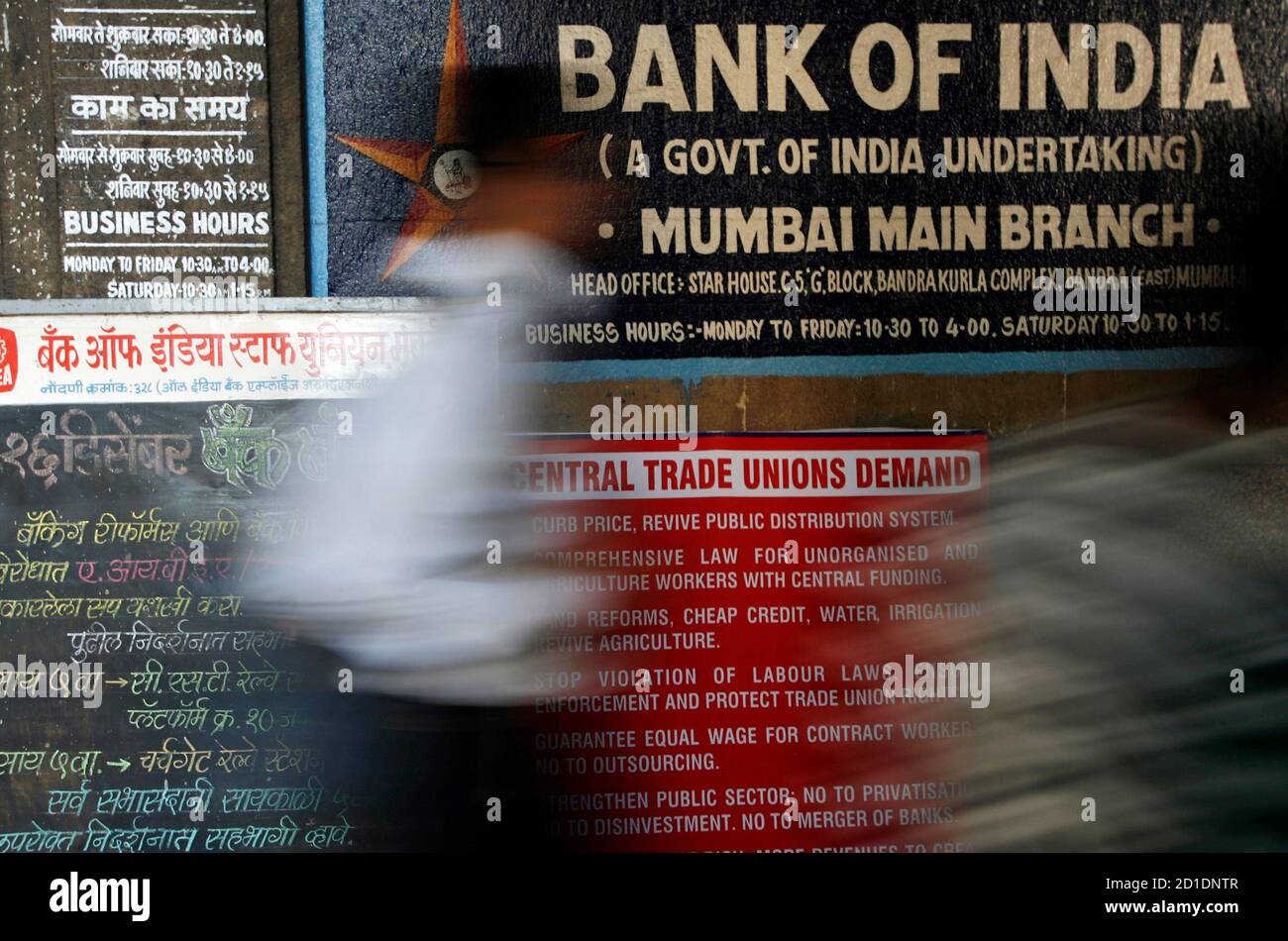 A man walks in front of a banner outside a state-run bank during a strike in Mumbai December 16, 2009. About 400,000 bank employees went on strike on Wednesday to protest merging state-owned banks, partially affecting cash transactions and clearing operations, a bank union official said. REUTERS/Arko Datta (INDIA - Tags: BUSINESS) Stock Photo