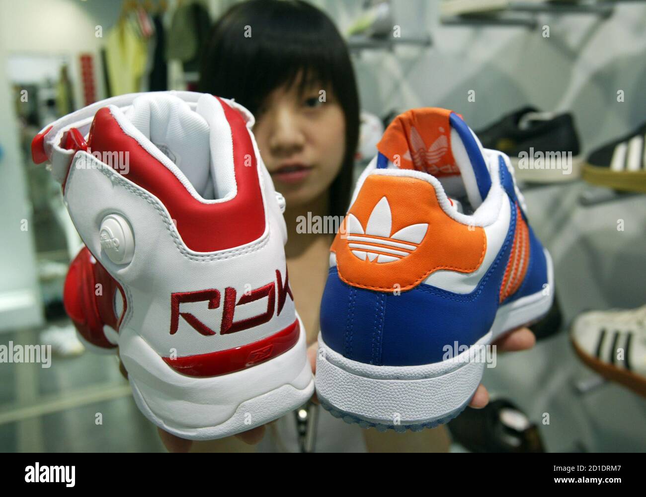 A saleswoman holds up athletic shoes by Reebok and Adidas in Taipei August  4, 2005. Adidas-Salomon plans to buy Reebok for 3.1 billion euros ($3.8  billion), merging the top two customers of