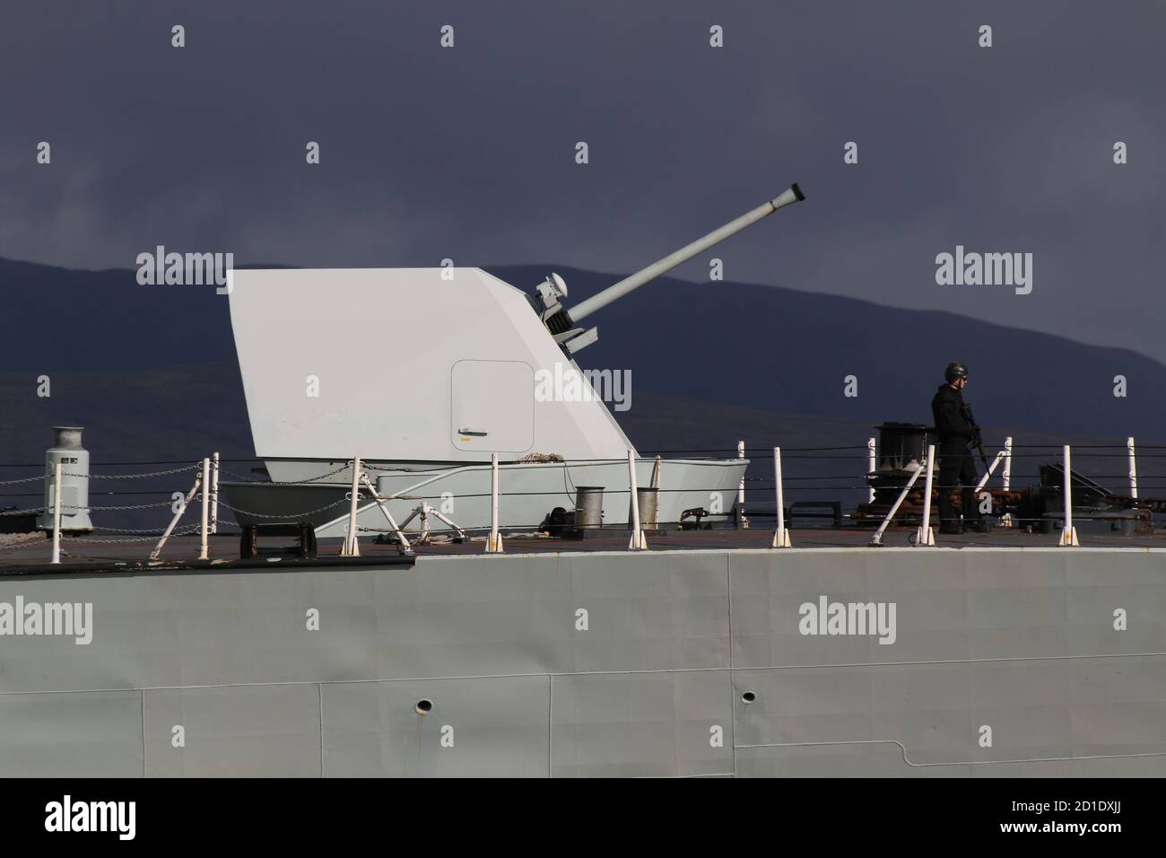 A Mark 3 Bofors 57mm naval gun, used on HMCS Ville de Quebec (FFH-332), a Halifax-class (or City-class) frigate operated by the Royal Canadian Navy, photographed as the vessel passed Greenock on her arrival for Exercise Joint Warrior. Note the armed sailor patrolling the deck. Stock Photo