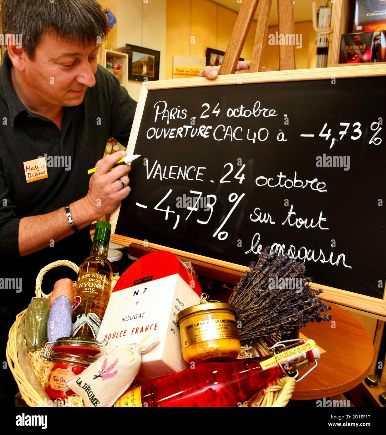 French shopkeeper Patrick Gardin, indicates the price reduction, less  4.73%, on a display board in his shop "Made in Drome" in Valence,  southeastern France, October 24, 2008. On days when the Paris