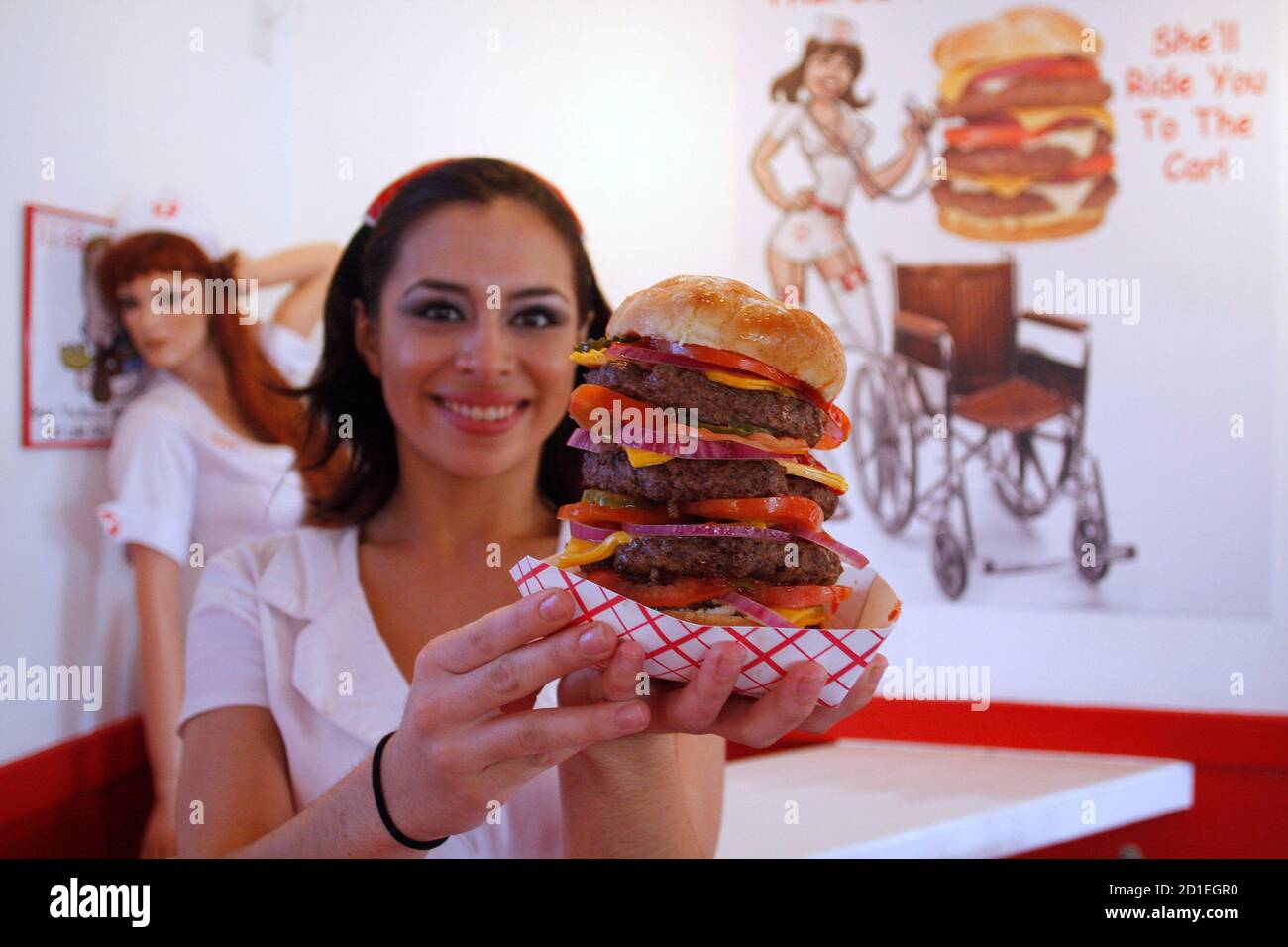 Waitress Mary Brasda poses with a "Quadruple Bypass Burger" at the Heart  Attack Grill in Chandler, Arizona June 17, 2009. The restaurant is known  for its hospital theme and triple and quadruple