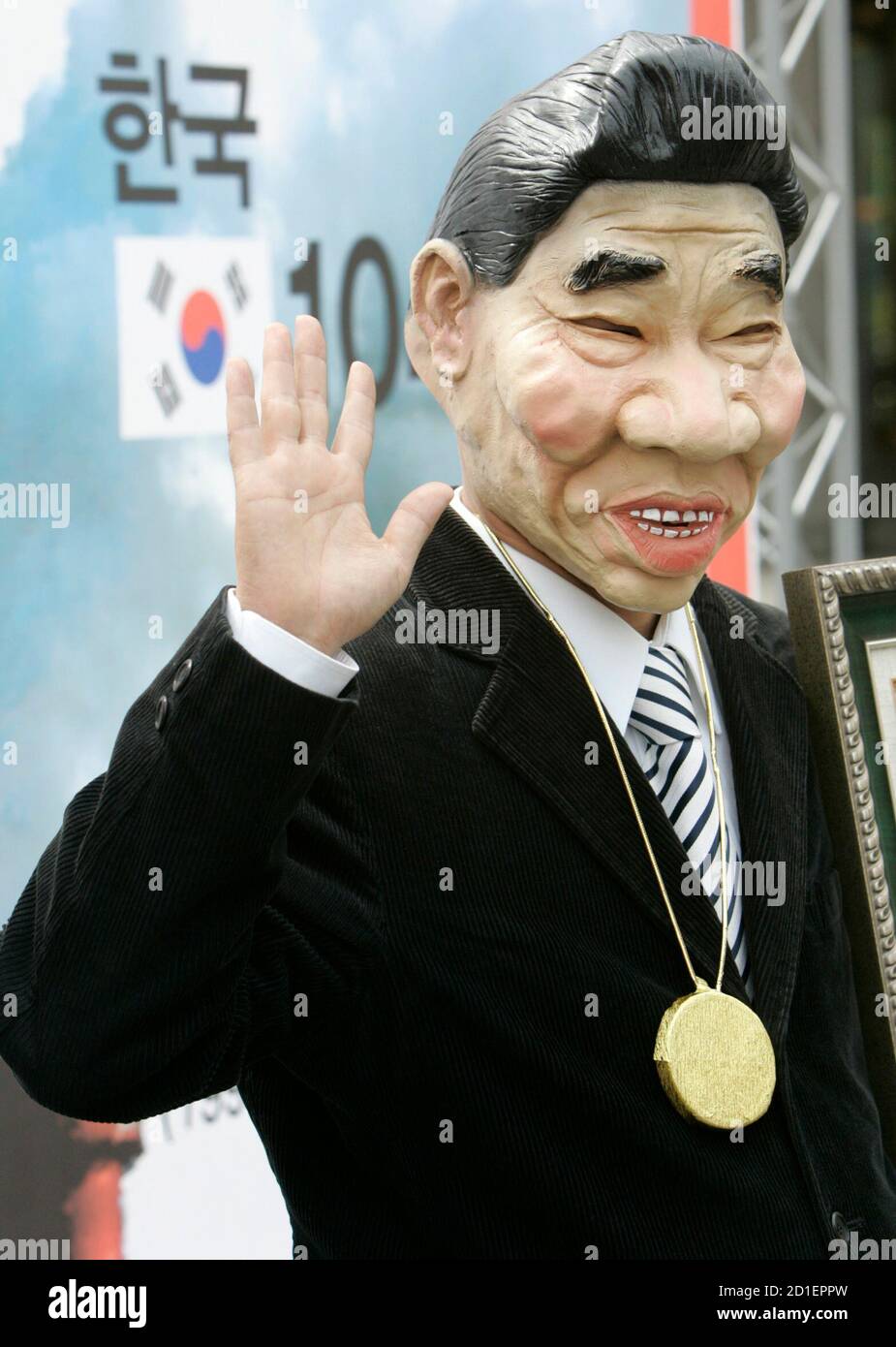 An environmental activist wearing a South Korean President Roh Moo-hyun mask waves after he received a prize for the contribution towards climate disaster during a performance denouncing the government's environmental policy in central Seoul April 6, 2007. Korean Federation for Environmental Movement (KFEM) said on Friday, quoting the statistics of the International Energy Agency (IEA), that carbon dioxide emissions in South Korea from 1990 to 2004 is 104.6 % increase as the highest in the world.  REUTERS/Jo Yong-Hak (SOUTH KOREA) Stock Photo