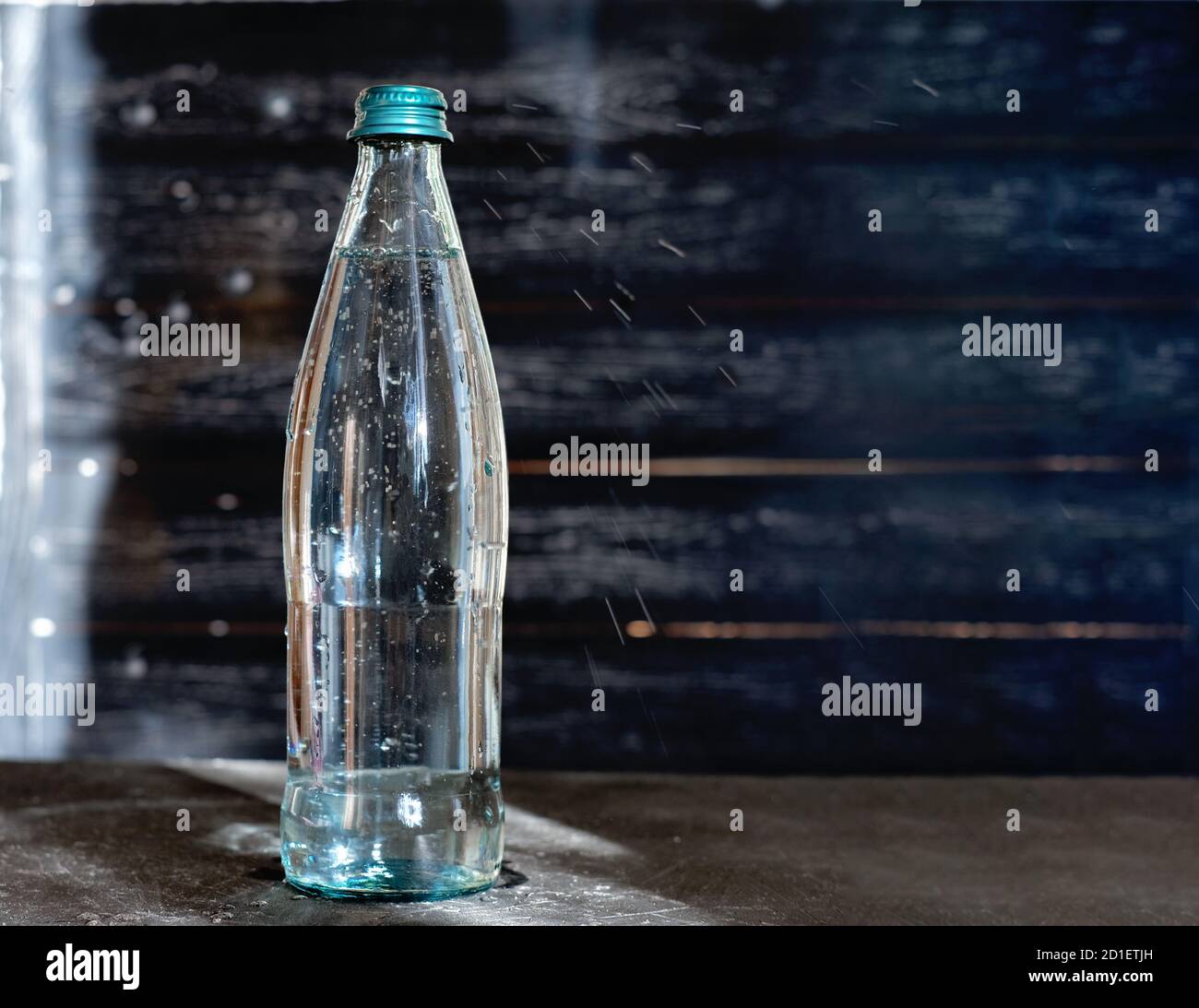 glass bottle of mineral water on grey table. sparkling water in a glass
