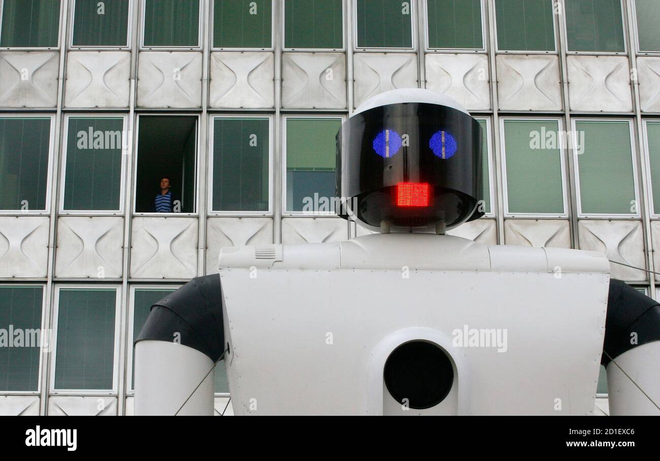 A man standing at the window listens to robot Robovox reading a mobile phone text message aloud in a synthetic voice in Ljubljana June 17, 2008.  This art installation set up by artist Martin Briclij and his team Codeep is 8 metres high and will be on show till June 22.  REUTERS/Srdjan Zivulovic  (SLOVENIA) Stock Photo