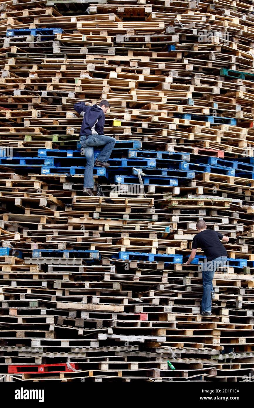 Youths climb a bonfire in the Protestant Ballycraigy estate in Antrim,  Northern Ireland July 10, 2009. On July 11 every year, Protestants and  Loyalists light bonfires to commemorate King William of Orange's