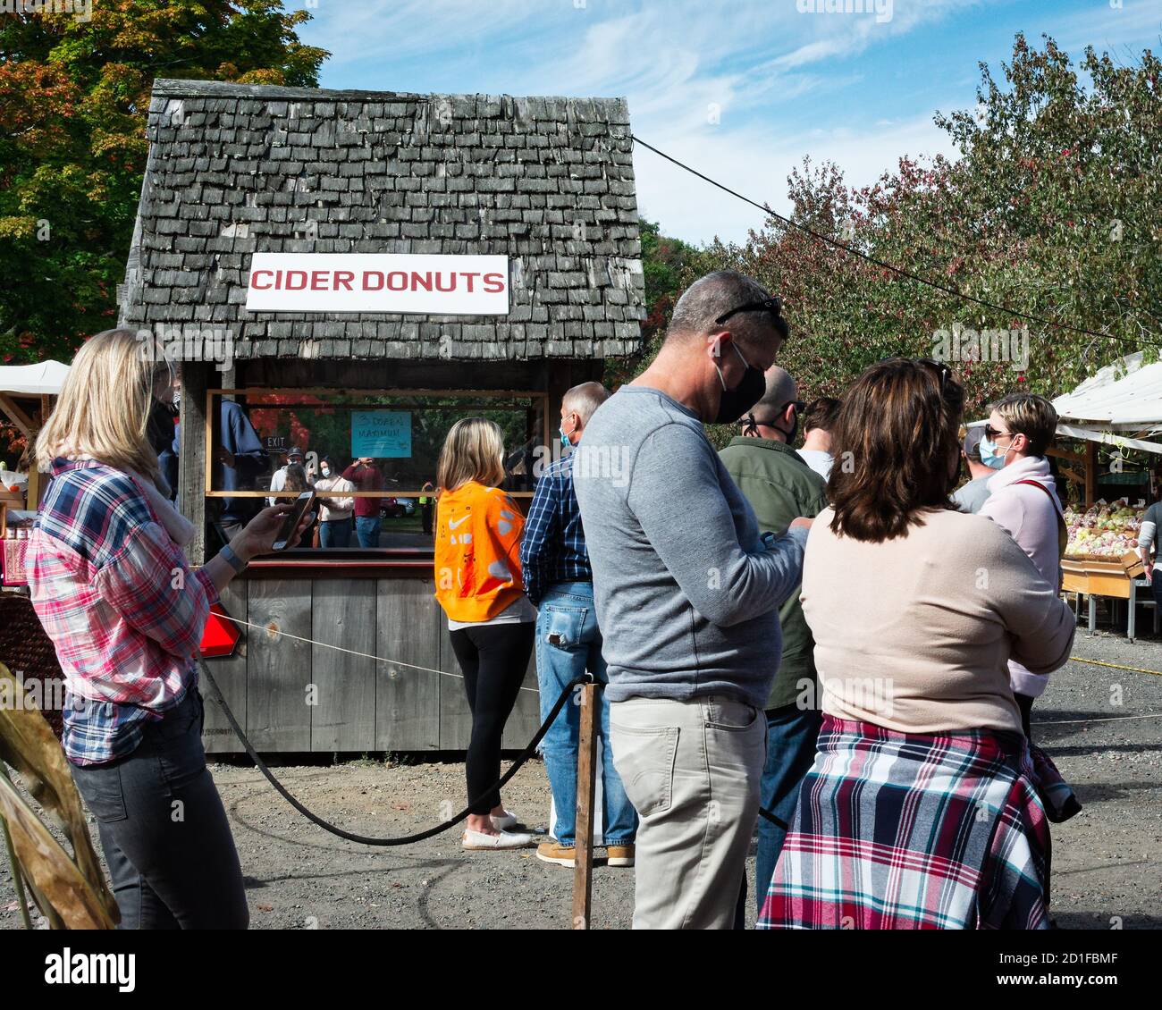 Customers at a New England apple picking farm wait patiently enforcing social distancing for fresh Cider Donuts to be made. Most of the patrons seem t Stock Photo