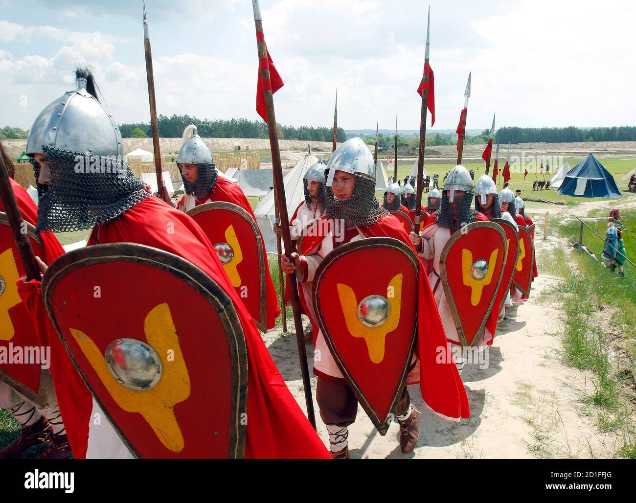 Men wearing medieval knight costumes walk to take part in a sword fight  performance during the international festival "The XIII century Kievan  Rus'" in the village of Kopachev, some 65 km (40