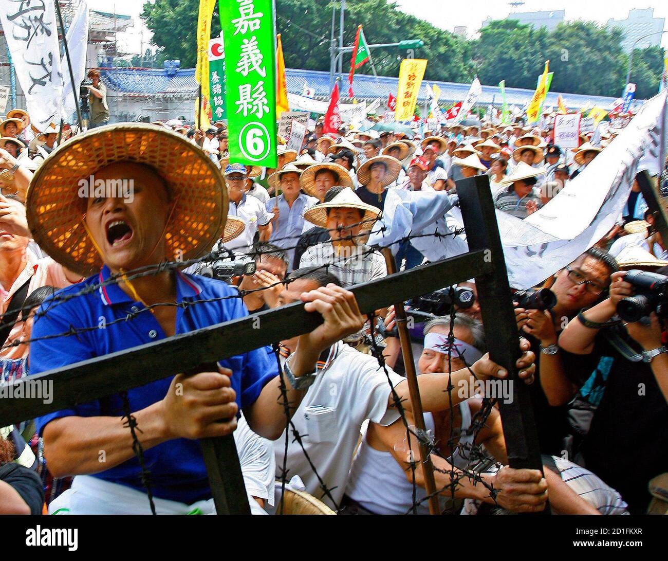 A pig farmer shouts as he climbs over a barricade during a demonstration in front of the Department of Health in Taipei August 21, 2007. Taiwan's government is to retain the ban on local use of ractopamine, an animal drug, while allowing foreign imports containing the same substance to enter Taiwan.   REUTERS/Nicky Loh (TAIWAN) Stock Photo