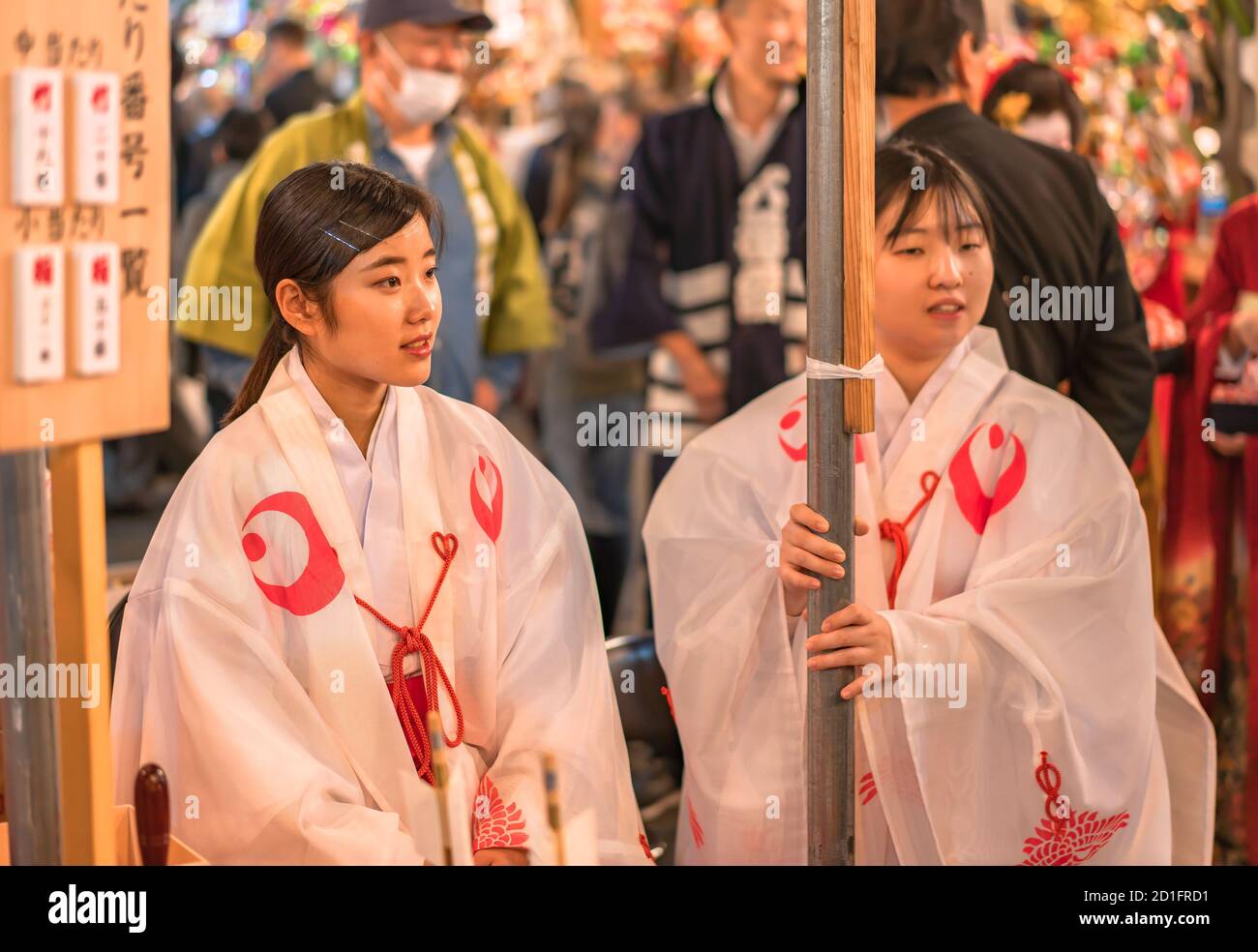 asakusa, japan - november 08 2019: Two young Japanese Miko maiden girls dressed in traditional white shōzoku kimono at the Shinto Ootori shrine during Stock Photo
