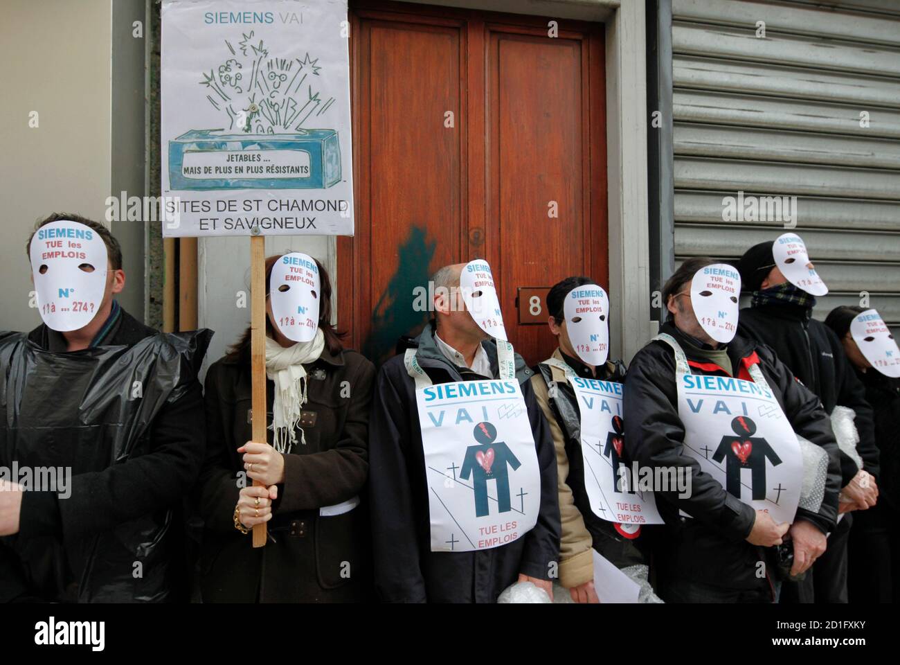 Employees of industrial conglomerate Siemens wear masks as they demonstrate to protest the closing of their factory in Saint-Chamond, south eastern France, February 4, 2010. The slogan reads 'Siemens kill jobs'.  REUTERS/Robert Pratta  (FRANCE - Tags: EMPLOYMENT BUSINESS) Stock Photo