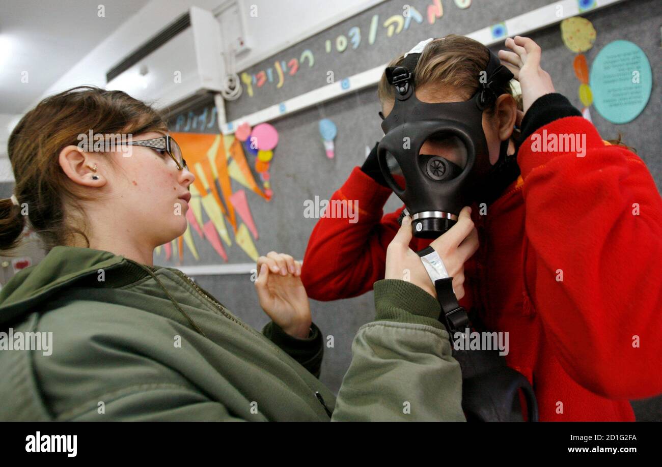 A soldier helps a student put on a gas mask during a drill simulating a  chemical attack on a school in Lod near Tel Aviv March 15, 2007.  REUTERS/Gil Cohen Magen (ISRAEL