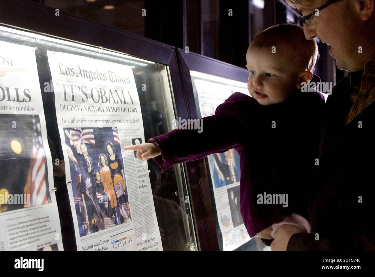 Nora Sherman, 18 months old, and her father Paul Sherman of Washington view the front pages of Wednesday's newspapers from around the world on display outside the Newseum in Washington November 5, 2008. Americans woke with joy, cautious optimism and frank worry on Wednesday after the historic win by Democrat Barack Obama, who went from long shot to president-elect on the promise of change.   REUTERS/Molly Riley   (UNITED STATES) Stock Photo