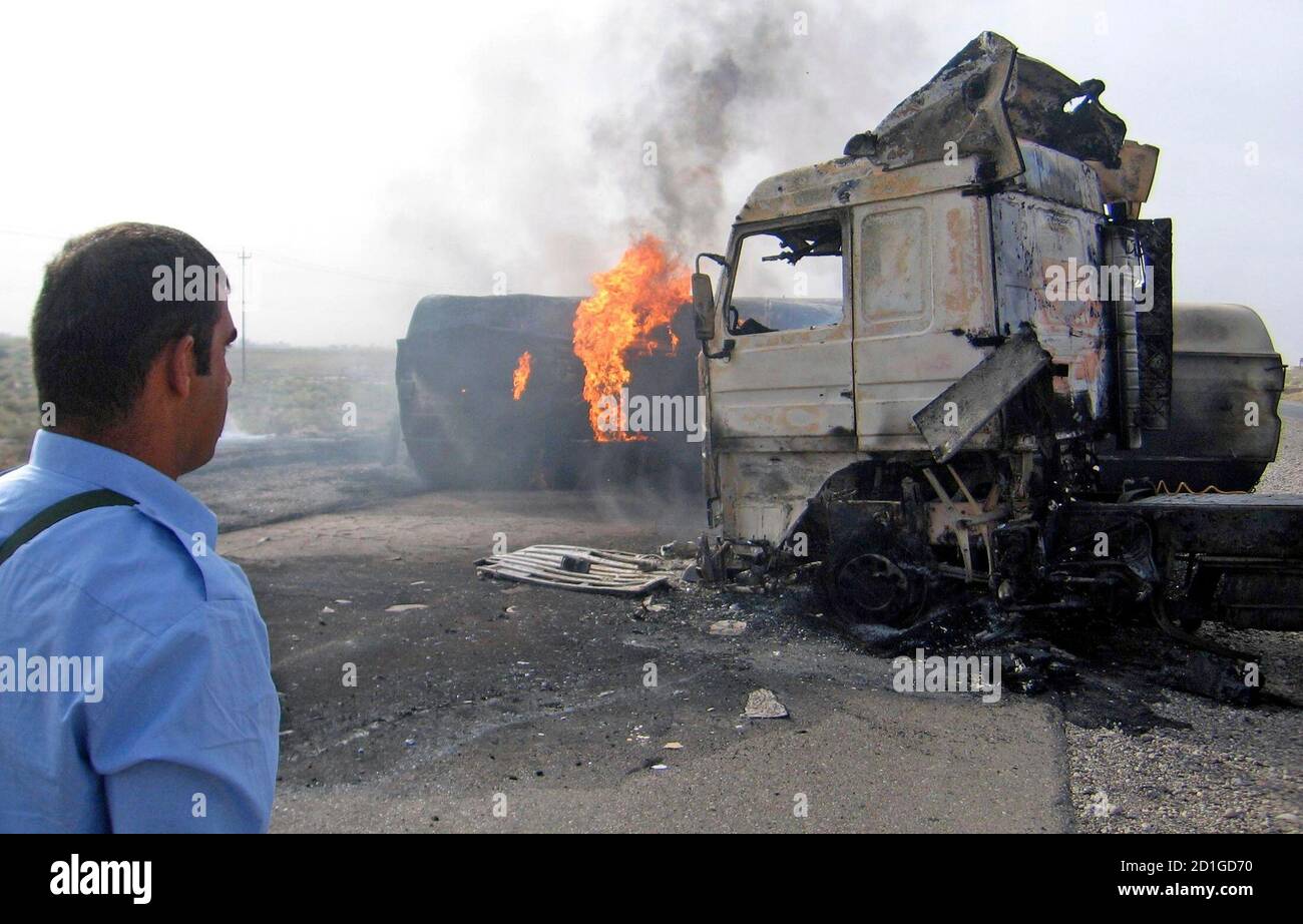A police officer looks at burning oil tankers after two roadside bomb attacks near Samara, 96 km (60 miles) north of Baghdad October 2, 2006. The twin attacks targeting oil tanker convoy killed two civilians, police said. REUTERS/Nuhad Hussin        (IRAQ) Stock Photo