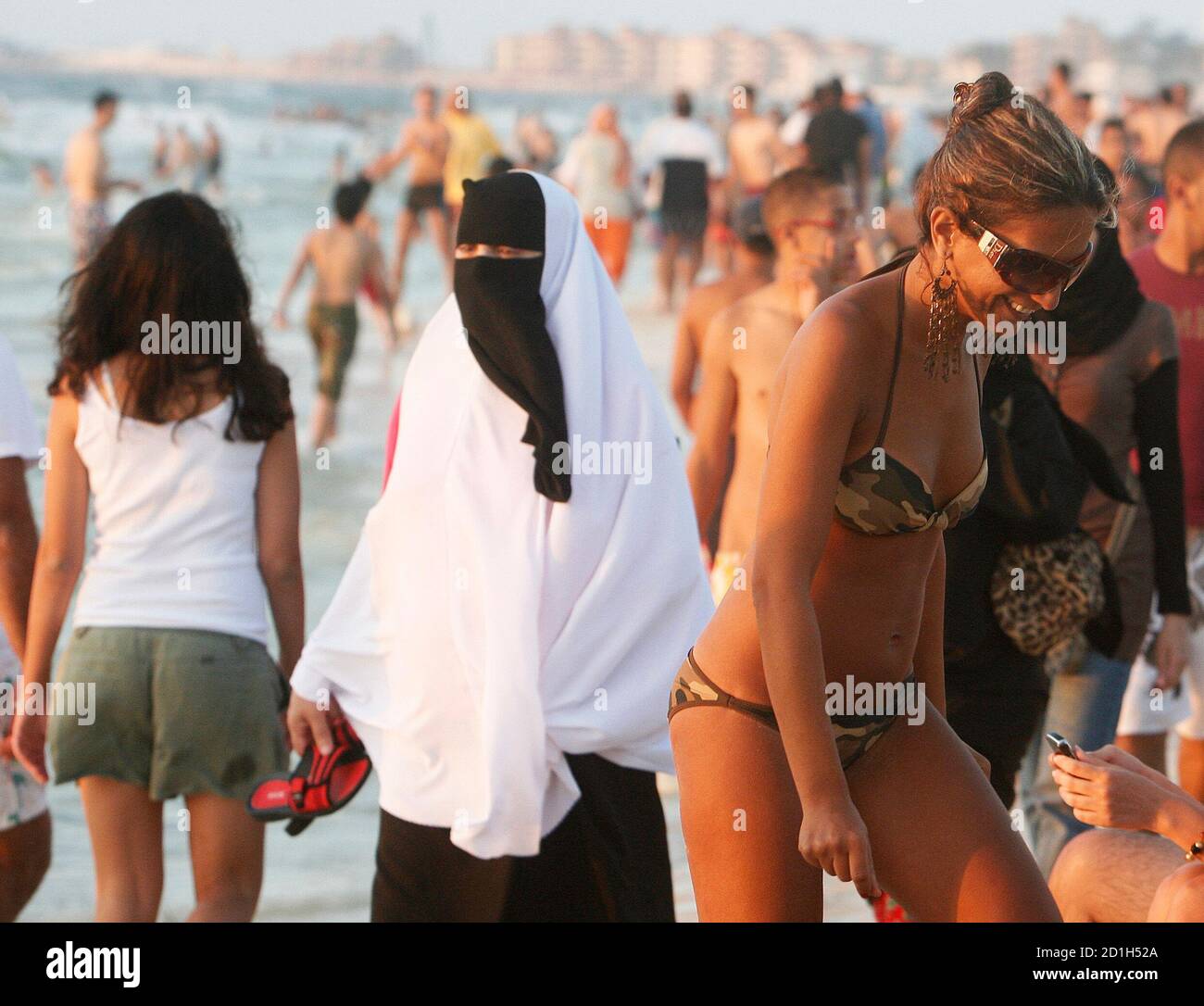 A woman wearing a bikini walks past a woman wearing a niqab on a beach in  the Mediterranean city of Alexandria, about 220 km northwest of Cairo,  August 7, 2009. REUTERS/Asmaa Waguih (
