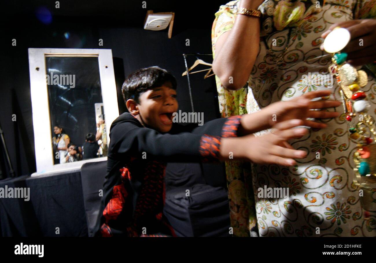 Azharuddin Ismail, who acted in the film "Slumdog Millionaire", plays with jewellery backstage before the start of the Ashima Leena fashion show on the second day of India Fashion Week in New Delhi March 19, 2009. REUTERS/Adnan Abidi (INDIA FASHION ENTERTAINMENT) Stock Photo