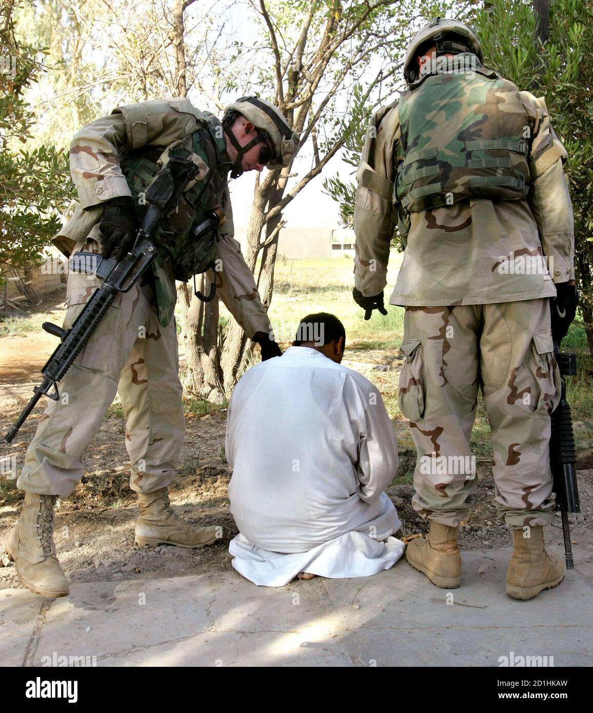 Two U.S. soldiers of the 3rd battalion, 7th Infantry, 4th Brigade, 3rd Infantry Division from Ft Benning, Georgia guard a detained suspect during a raid searching for illegal weapons inside his house in Baghdad August 3, 2005. Fourteen Marines were killed in a roadside bomb blast in western Iraq on Wednesday, the U.S. military said, in one of the single deadliest attacks against U.S. forces since the beginning of the war. REUTERS/Andrea Comas  ACO/TY Stock Photo