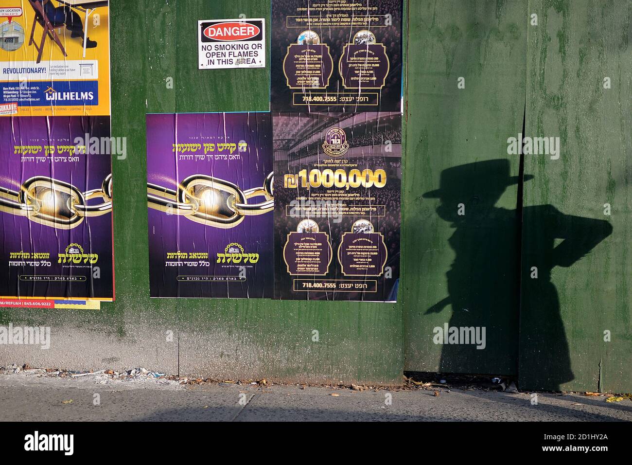 New York City, USA. 05th Oct, 2020. The shadow of a young Orthodox Jewsih boy wearing a mask passes along a boarded up home along 14th Avenue in the Borough Park section of Brooklyn, one of nine zip code neighborhoods that have seen a positive coronavirus test rate over 3% in the past seven days, in Brooklyn, NY, October 5, 2020. Nine zip codes throughout Queens and Brooklyn have become hot spots defined as rise in COVID-19 infections over several days, Gov. Cuomo said he would meet with leaders of the Orthodox Jewish community. (Anthony Behar/Sipa USA) Credit: Sipa USA/Alamy Live News Stock Photo