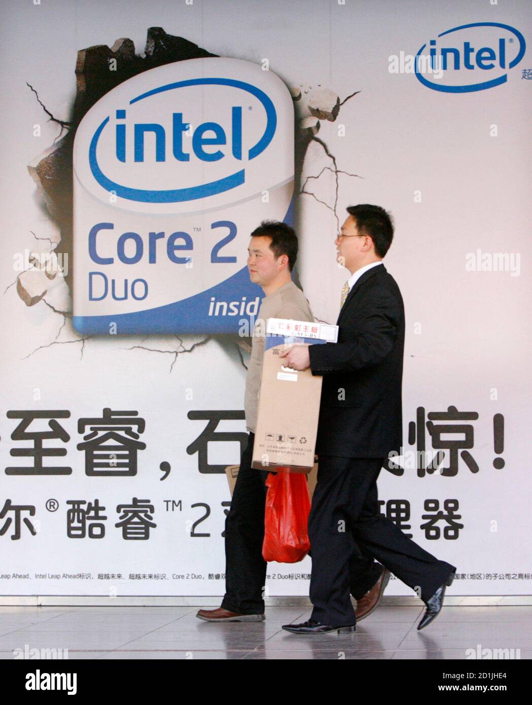 Shoppers carry new computers past an Intel Core Duo advertisement outside a  computer shop in Beijing March 26, 2007. Chip giant Intel Corp. said on  Monday it would invest $2.5 billion to