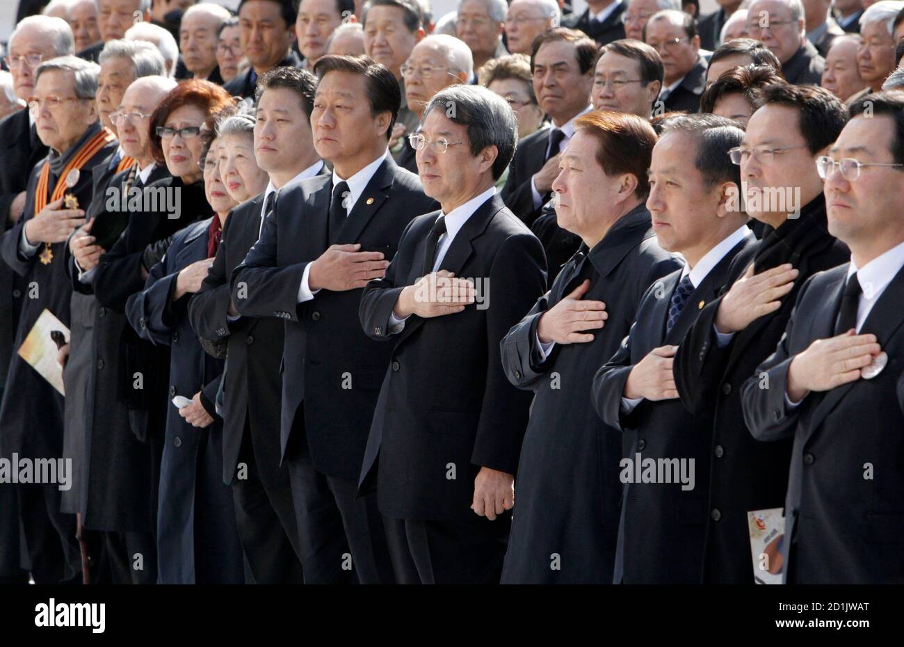 South Korean Prime Minister Chung Un-chan (5th R, front row), government officials and citizens salute the national flag during a ceremony at the Seoul City Hall Plaza March 26, 2010, to commemorate the 100th anniversary of Japan's execution of Korean independence fighter Ahn Jung-geun. Ahn was the man who shot to death Hirobumi Ito, the first Japanese Resident General of Korea, in China's northeastern city of Harbin in October 1909. Japan had forcibly occupied and colonized the Korean peninsula in 1910-1945.     REUTERS/Jo Yong-Hak (SOUTH KOREA - Tags: ANNIVERSARY POLITICS) Stock Photo