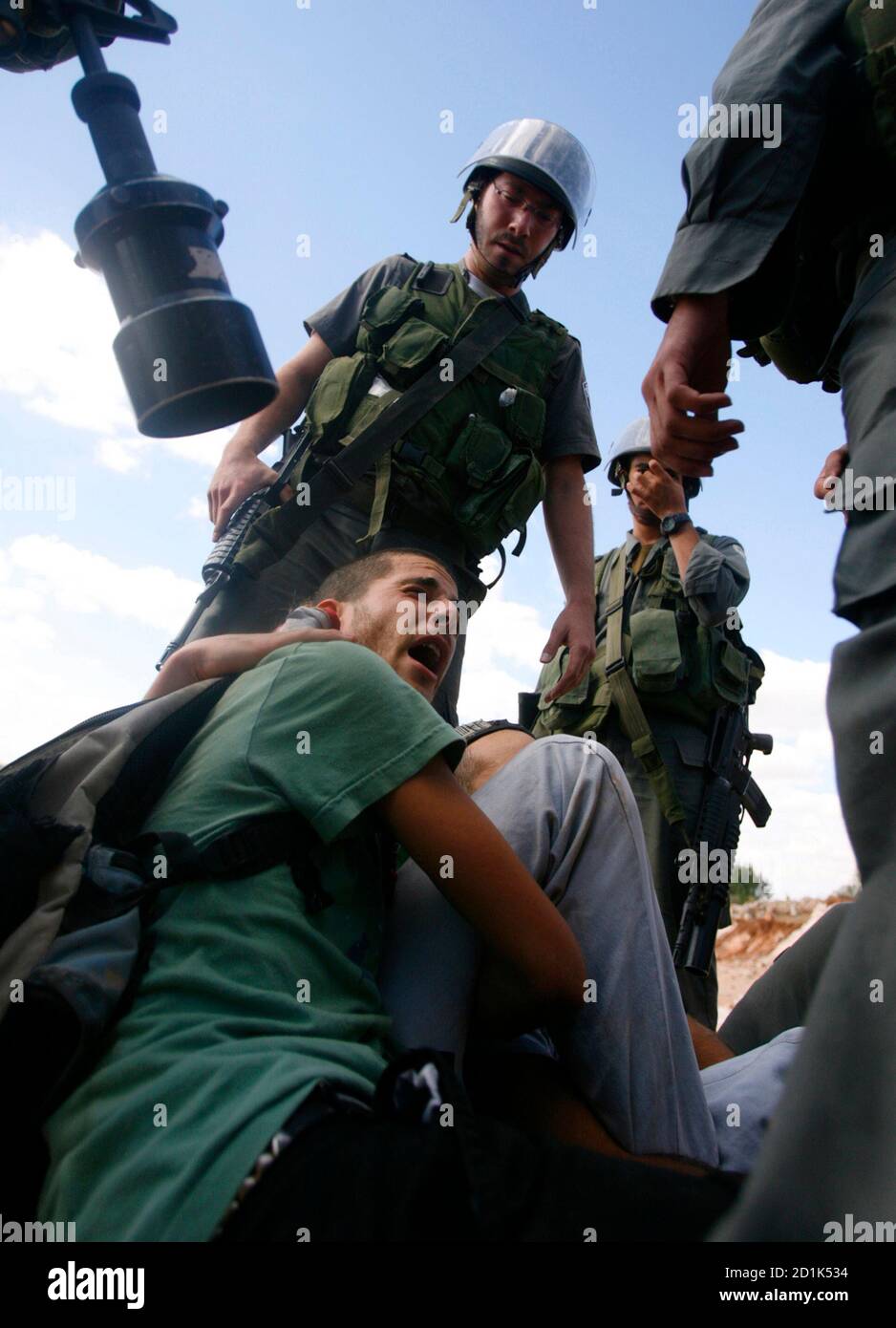 Israeli border police officers detain an Israeli activist of the Rabbis for Human Rights movement (RHR) after activists joined Palestinians for the olive harvest near the construction site of the controversial Israeli barrier in the West Bank village of Nilin, near Ramallah October 10, 2008.     REUTERS/Fadi Arouri (WEST BANK) Stock Photo