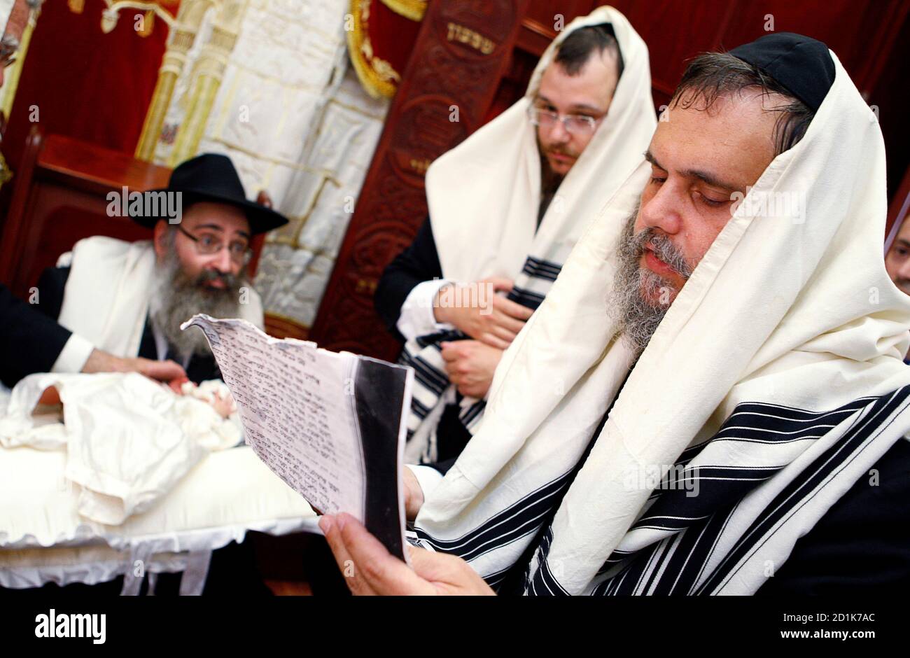 Rabbi Yehuda Matusof holds his eightdayold grandson Menachem Mendel (L) as other rabbis read