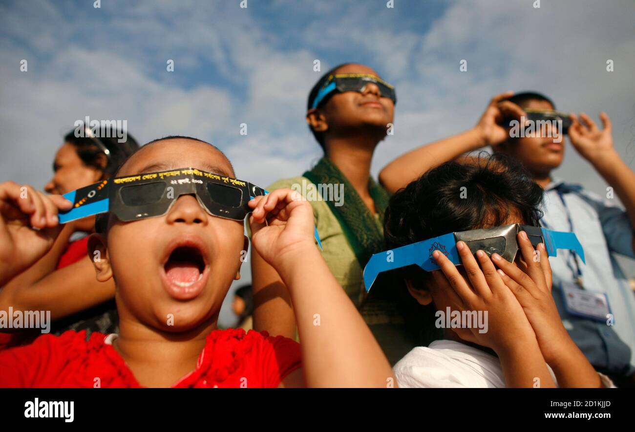 People use solar viewers to view a partial solar eclipse at the national  parliament complex in Dhaka July 22, 2009. A total solar eclipse on  Wednesday swept across a narrow swathe of